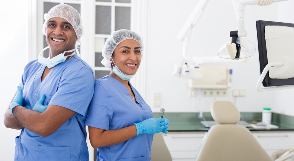 Dental Team Smiling in Clinic - Dentist in San Fernando Two dental professionals in scrubs smiling confidently in a modern dental office - Dentist in San Fernando