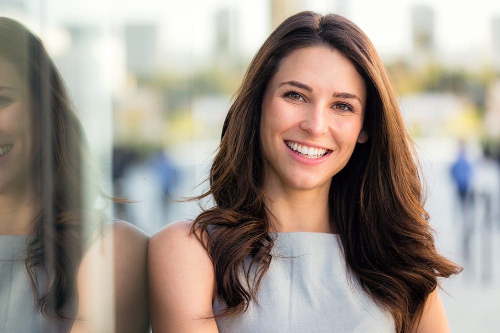 Professional Woman with Confident Smile A young professional smiles brightly, highlighting the value of dental care for confidence and success.