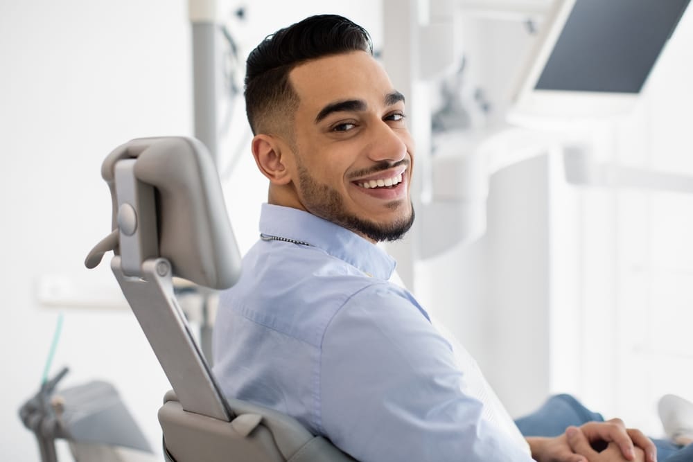 A relaxed man sits in a modern dental chair, looking back with a bright smile that reflects a positive dental experience – Dentist in Sylmar, CA.