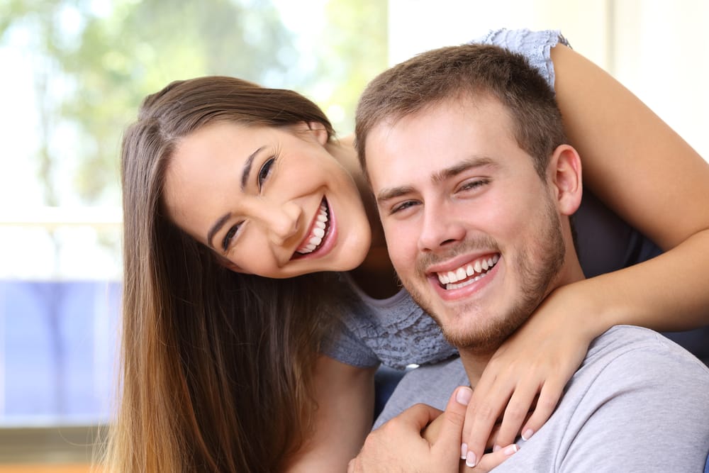 A joyful couple embraces and smiles brightly, capturing a moment of connection and confidence with their healthy teeth – Dentist in Sylmar, CA.